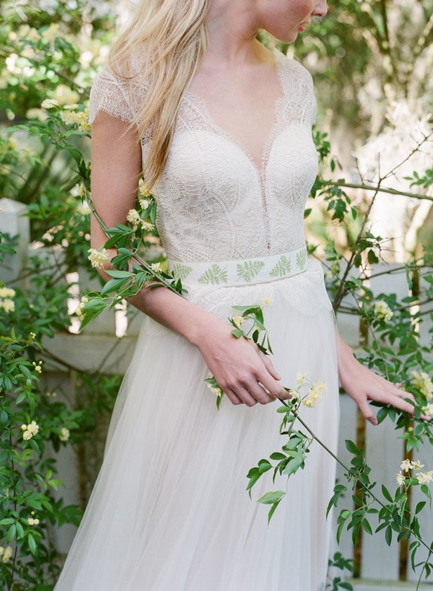 Divine Atelier’s “Celia” gown from Gown  Boutique of Charleston. Rock crystal and rose  gold ring from Roberto Coin. Green and fern ribbon used as a sash from style team’s  collection