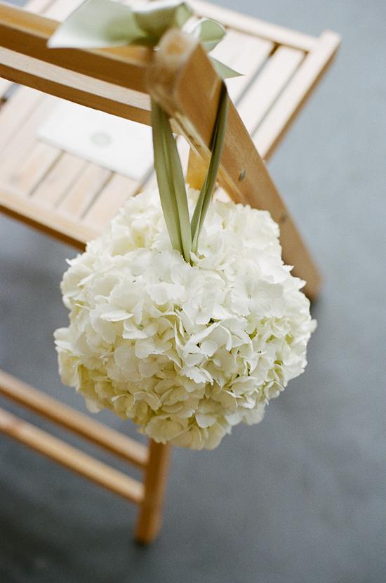TIED ON: Jade Water Designs shaped lush spheres of white and green hydrangea, white peonies, and white ranunculus to accent ceremony seating.