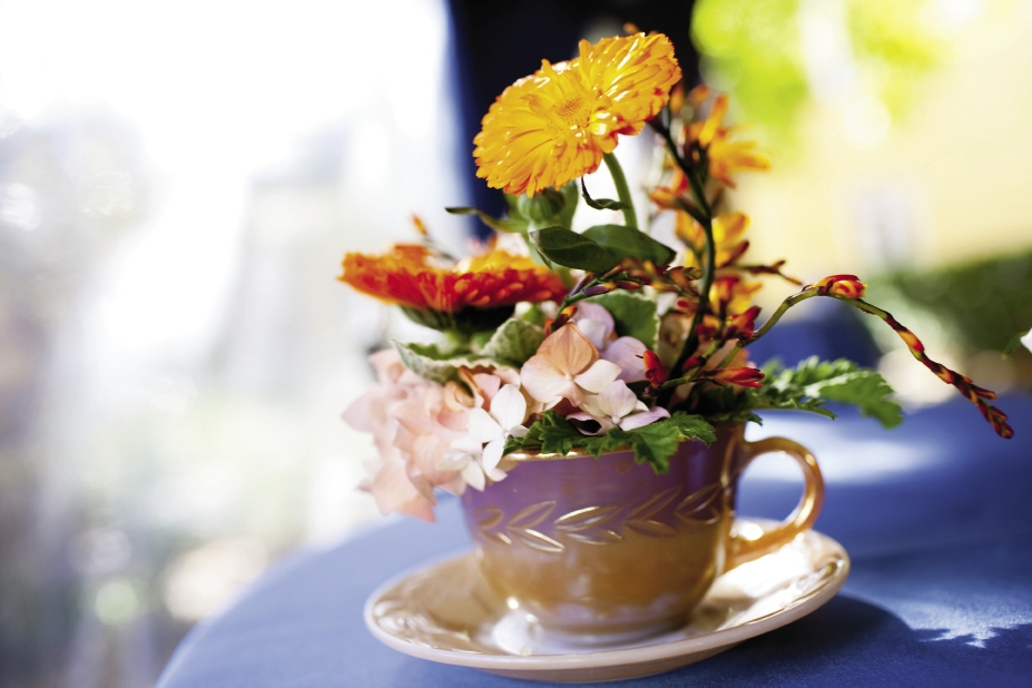 BLOOMING SET: Blossoms Events found delicate 1940s lusterware used the cups and vessels to cradle arrangements of orange calendula and peach astilbe.