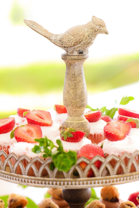 CHARMING CHEWS: Sweet Reba’s topped the flavored cupcakes with fresh strawberries. The leafy garnishes and bird-topped stone stand gave the setup a secret garden feel.