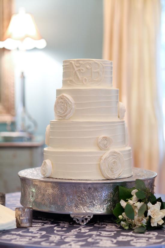 SUGAR RUSH: Ogled at by guests, the four-tiered wedding cake was designed by Lauren Mitterer of WildFlour Pastry and decorated with an edible monogram. The textures of the white confection, the hammered silver cake stand, and the printed linen added depth to the display.
