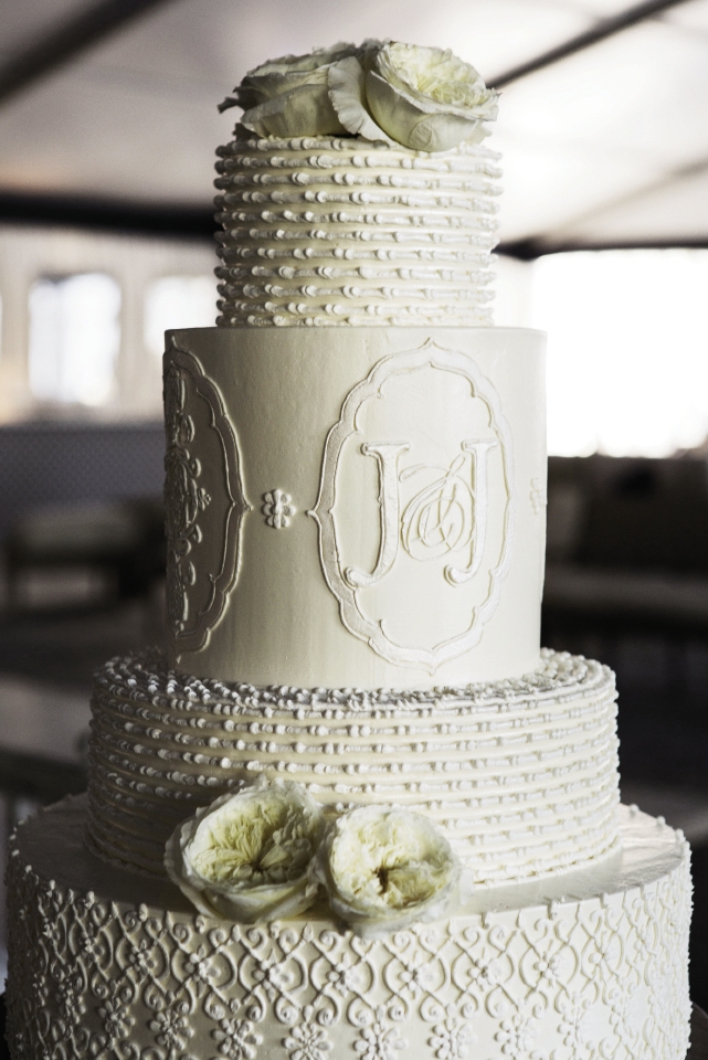 TONE ON TONE: Wedding Cakes by Jim Smeal replicated the monogram and invitation pattern in ivory  buttercream on an immaculate cake before adding fresh garden roses for accents.