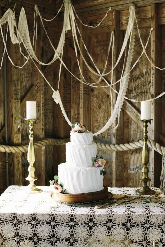 Amelia flanked her mother’s pound cake with her grandmother’s brass candlesticks and draped heirloom lace remnants to sync with the crocheted tablecloth that belonged to her groom’s great-grandparents. Cake by bride’s mother. Wedding design by bride. Image by Susan Dean Photography at Bowens Island Restaurant.