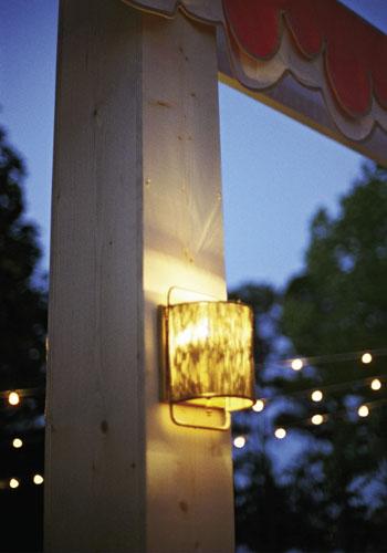 You&#039;re Glowing: Shaded sconces hung from custom-made wooden pillars that camouflaged metal tent poles.