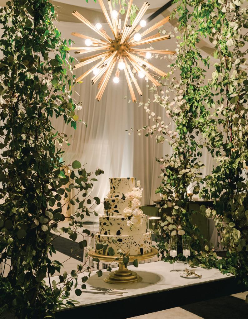Designed to mimic the popular marble-chip composite terrazzo, the cake sat suspended on a vine-covered trellis beneath a shining Sputnik chandelier. “As it turns out, cutting a swinging cake is tricky,” recalls Emily, “but it was swiftly removed and set onto a stable surface.”