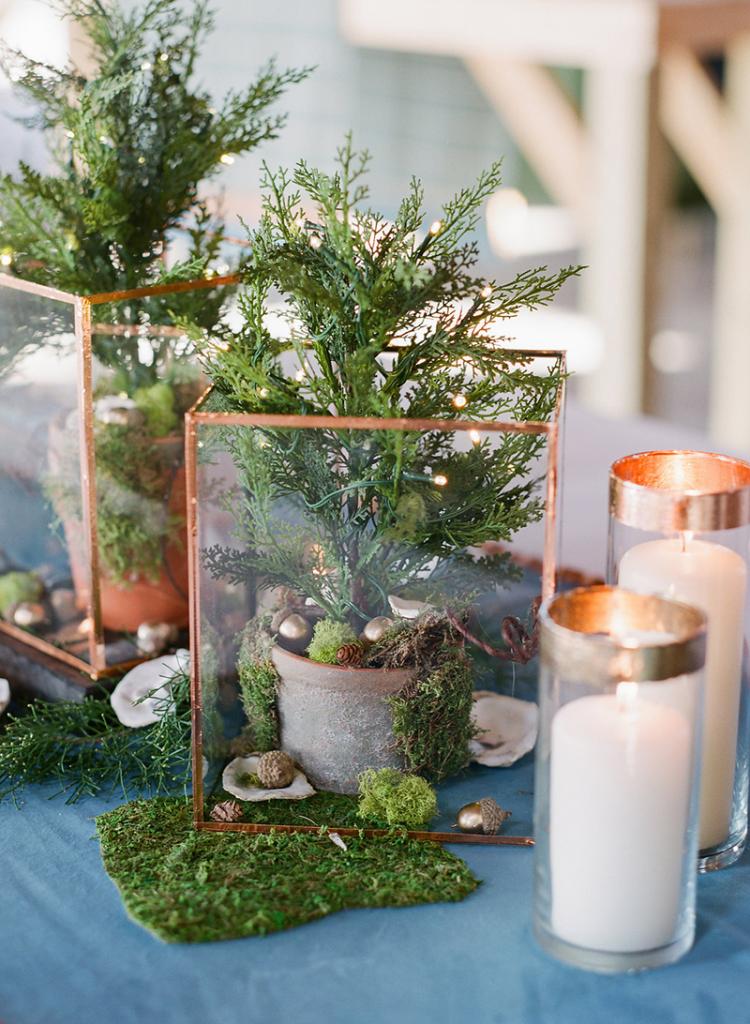 The bride and her mother glued together glass frames trimmed in copper foil to form terrariums they filled with potted firs and flanked with Dollar Tree vases they’d edged in gold