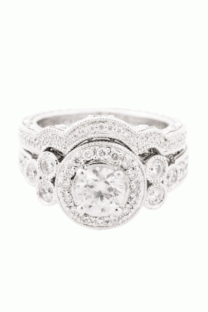 TWICE AS NICE: 14K white gold ring ($2,855, setting only) with a bezel setting and halo of pavé diamonds flanked  by trios of round-cut diamonds (.58 total cts.) and a matching “shadow” band ($1,359) inset with pavé  diamonds, Skatell’s Manufacturing Jewelers