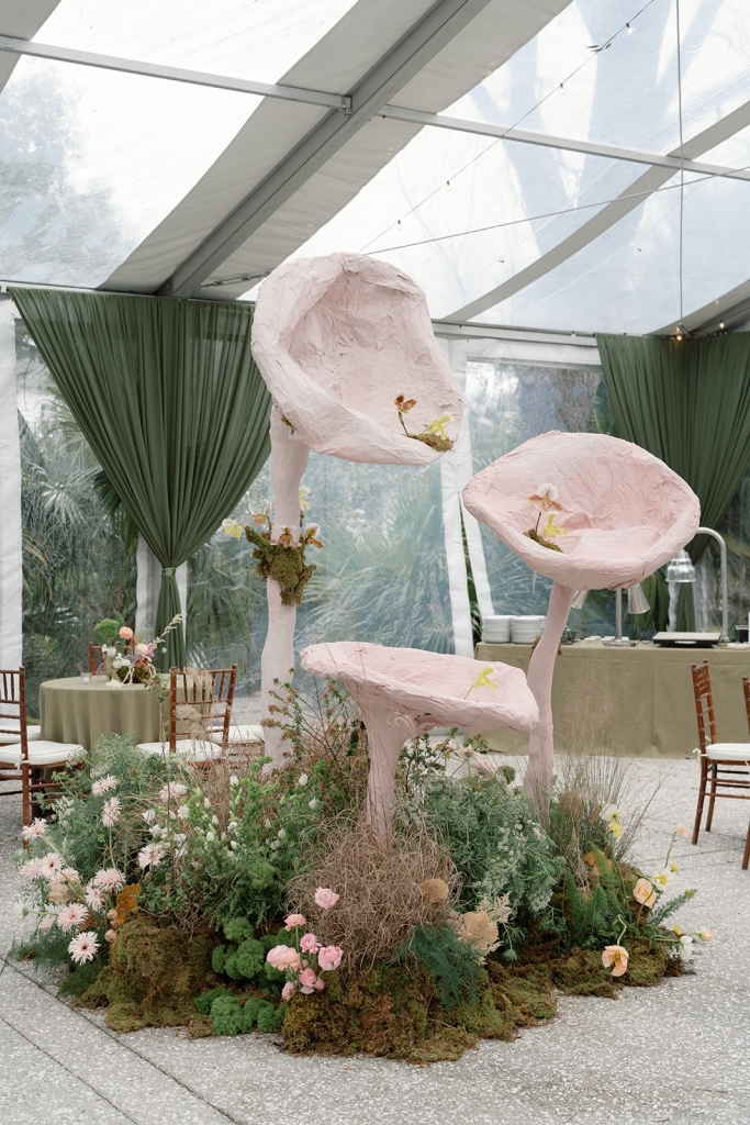 Atypical wedding florals climbed, draped, and spilled across floors, and two larger-than-life pink plaster oyster mushroom installations created by florist Petaloso brought magical rain forest vibes. The entryway installation (pictured) was a showstopper. The theme was inspired by the bride’s favorite childhood movie, FernGully: The Last Rainforest.