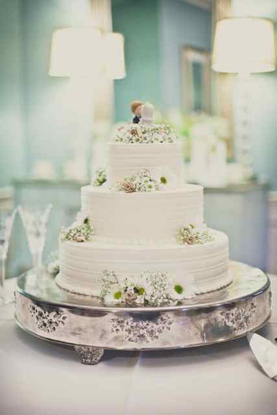 FLOWER POWER: The three-tiered confection by Twenty Six Divine was dressed with daisies, miniature palmetto roses, and a vintage cake topper.