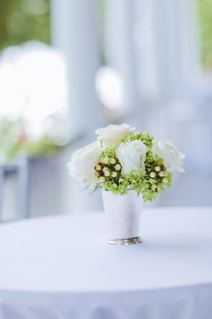 WHITE DELIGHT: White roses, hydrangea, and hypericum berries were placed in mint julep cups for delicate centerpieces.