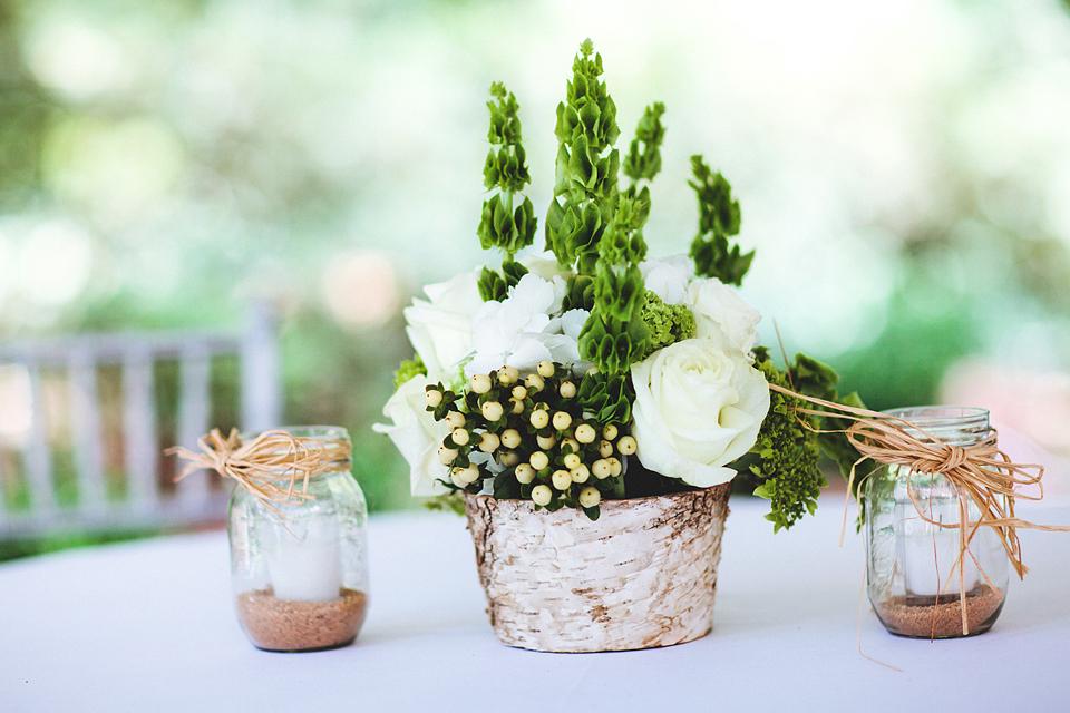 DAINTY DOES IT: Petite groups of Belles of Ireland, white roses, and hypericum berries were bookmarked by Mason jars filled with sand and votive candles.