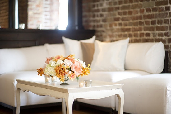 TALK OF THE TABLE: Floral arrangements stood against white sofas and tables and the exposed brick walls of the Historic Rice Mill House.