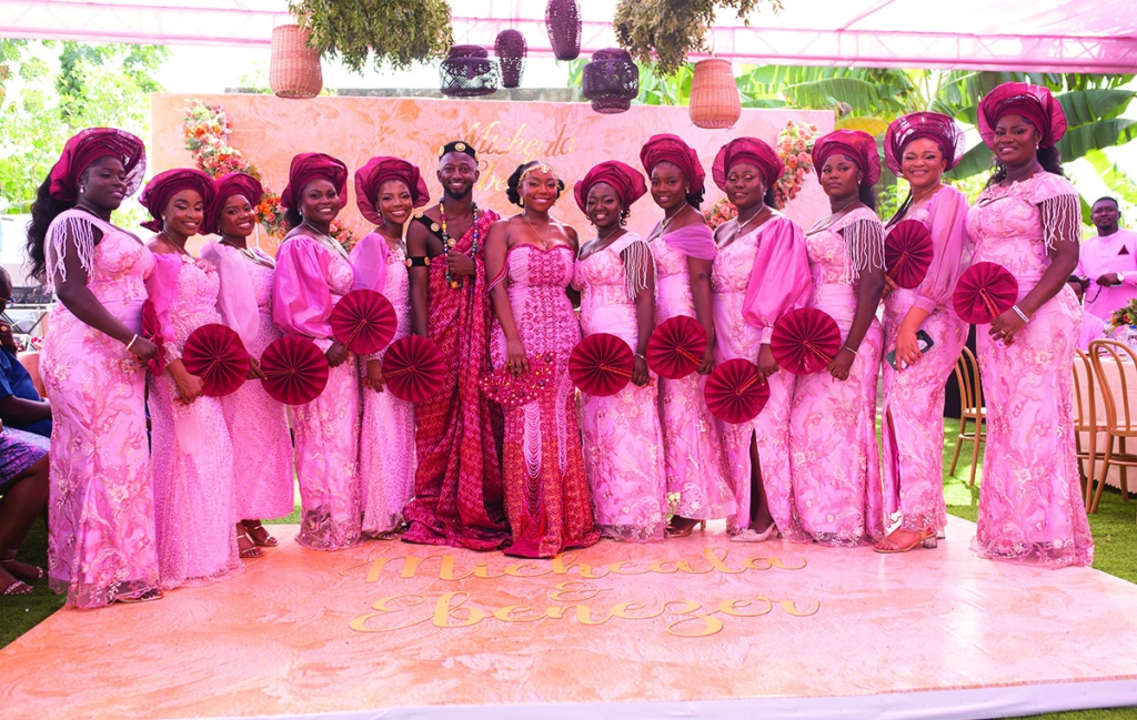 To balance the soft pink color of the bridesmaids’ gowns, Micheala selected a ruby hue for the gele (traditional head wraps) and bridal fans, a popular accessory in Ghana.