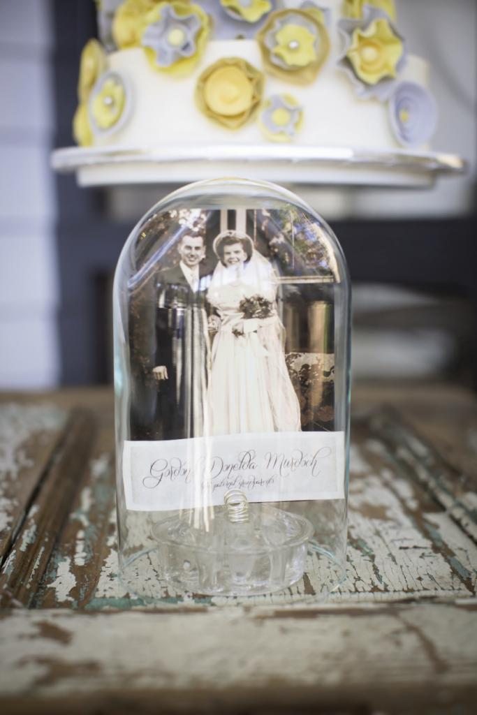 HISTORY LESSON: Sarah and Chris honored their familial roots with  wedding snapshots of their parents and grandparents. Here, Sarah secured a 1947 photo of Chris’ grandparents Gordon and Donelda Murdoch with a vintage flower frog and displayed it under a glass cloche for safekeeping.