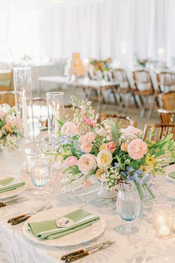 Table settings were playful yet elevated thanks to tortoiseshell flatware, linen pattern play, and colorful pastel florals; for the head table, Ruthie hand-painted guests’ names onto oyster shells.