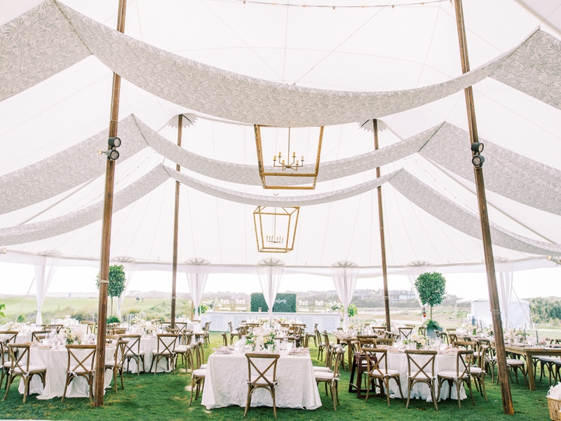 The grand reception tent exuded airy elegance with gilded hanging lanterns, topiary trees, and draped fabric that also adorned the front of the bar.