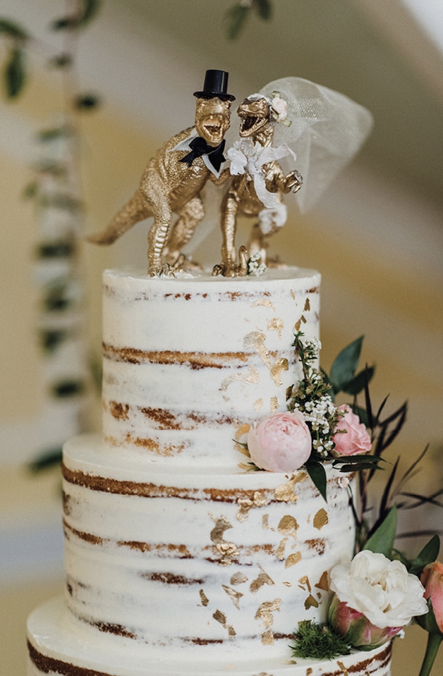 The golden dinosaur bride and groom cake toppers that Anna sourced. Even the nude cake by Patrick Properties presented the unexpected: the main layer was raspberry and the icing banana flavor.