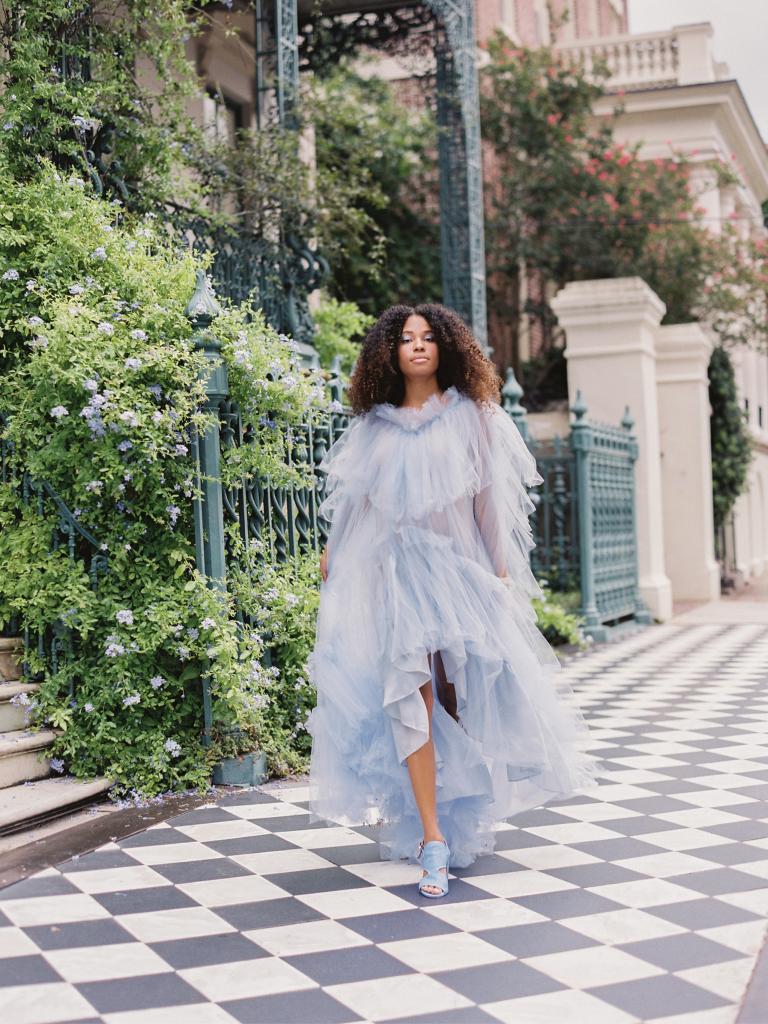 Elizabeth Dye’s silk organza and tulle, tiered trapeze gown is a versatile design that would be great for an elopement or intimate destination wedding, notes stylist Lindsey Nowak. The vining plumbago outside the John Rutledge House Inn added to the blue theme.