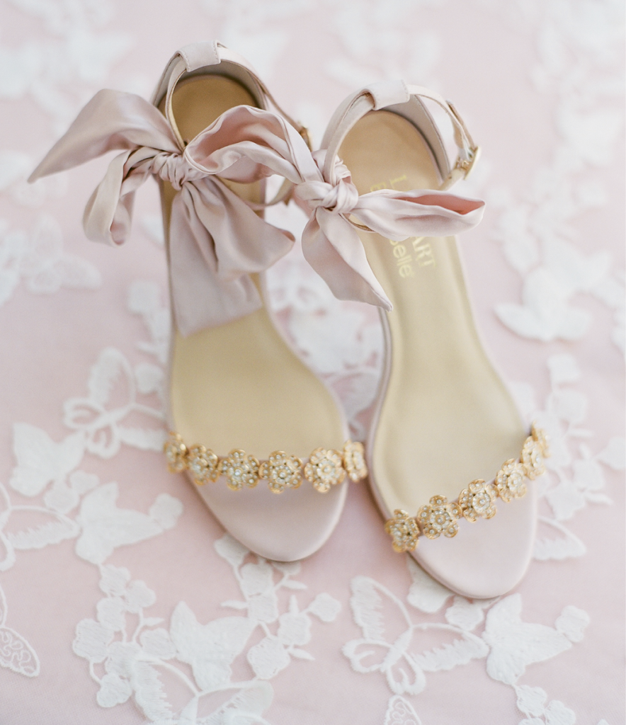 Dainty bloom accents and satin bows at the ankle make these heels spring goddess fare. A fan of flat-lay memento photographs? Share enough yardage of a favorite lace linen with your photographer to use in styled shots, then have a seamstress create table runners or tablecloths from it for your newlywed nest.