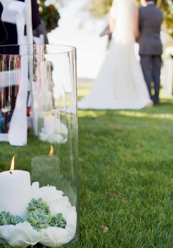 AISLE STYLE: White, vase-ensconced candles flickered from beds of sand topped with flower petals and silver-green succulents.