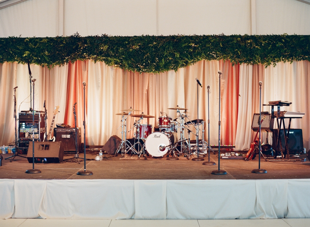 Ombré draping capped with a valance of greens gave the band (and the bride’s brother) a stunning stage on which to entertain the crowd. &lt;i&gt;Image by Lucy Cuneo Photography&lt;/i&gt;