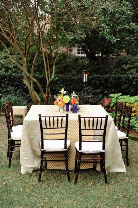 GARDEN PARTY: Square reception tables (which offset all the natural curves in the garden) were peppered throughout the reception. Blue-hued vessels with bright florals popped against the pale yellow- and cream-colored linens.