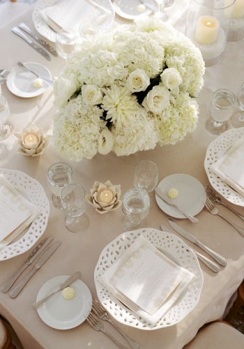 ZONE OF NEUTRALITY: Cream-colored hydrangeas and roses plus delicate white dinnerware and sculptural votive holders offset a khaki backdrop that, on its own, could have washed out the reception space.