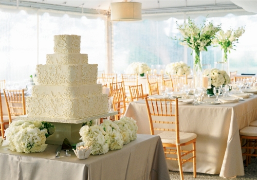 CHAMPAGNE DREAMS: “We used khaki and white stripes on the tablecloths to give everything a little bit of a preppy twist,” says Jane of the dining area, where Jim Smeal’s ivory wedding cake became part of the décor.